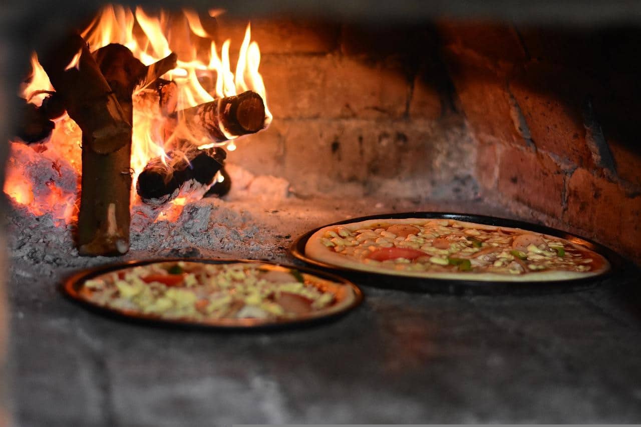 Image d'une pizza cuite sur un feu de bois extérieur